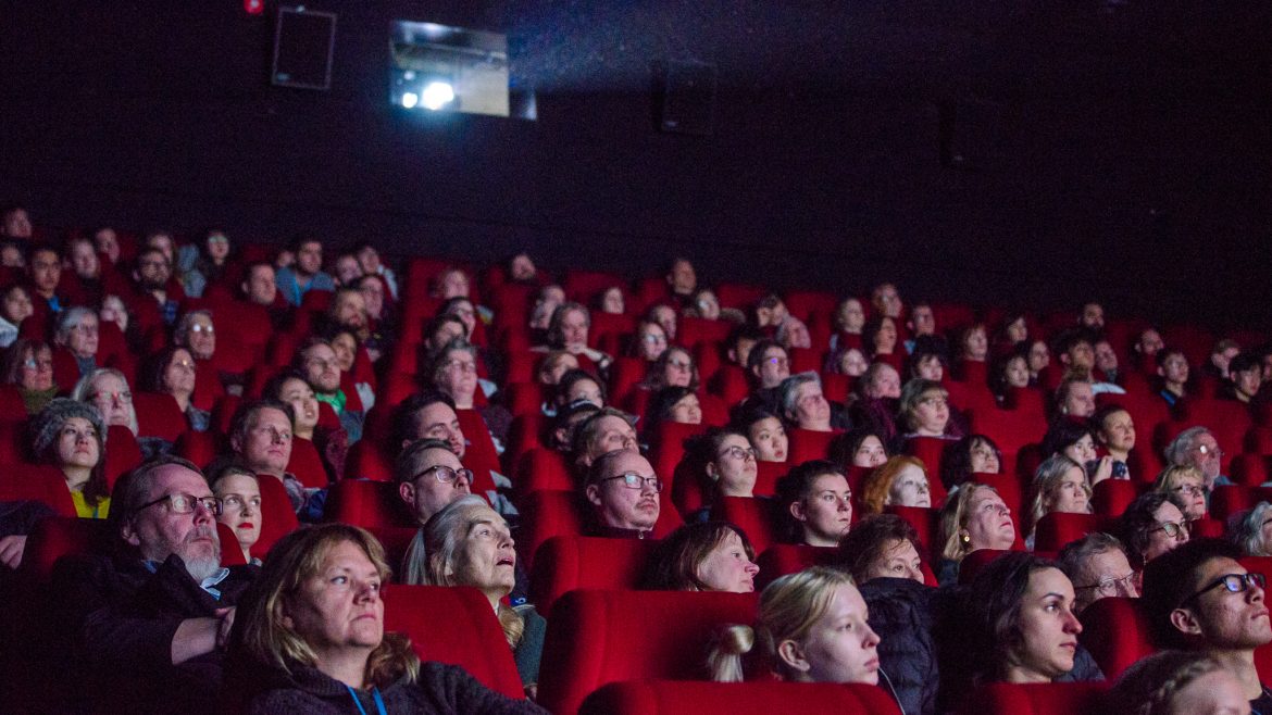Tampereen elokuvajuhlien yleisöä elokuvateatterin punaisilla penkeillä katsomassa elokuvanäytöstä.